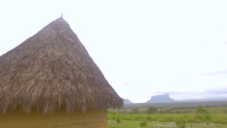 Indigenous-hut-in-Mayupa,-Canaima,-Venezuela,-with-amazing-tepuy-mountains-at-the-back-during-a-rainy-day