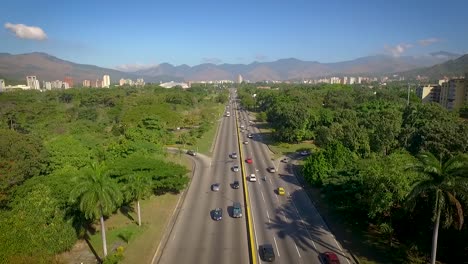 Aerial-shot-of-a-highway-in-Valencia,-Carabobo,-Venezuela,-next-to-a-green-park