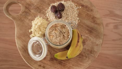 Oatmeal-With-Dried-Dates-and-Bananas-next-to-it-on-Wooden-Table,-Top-Down-View
