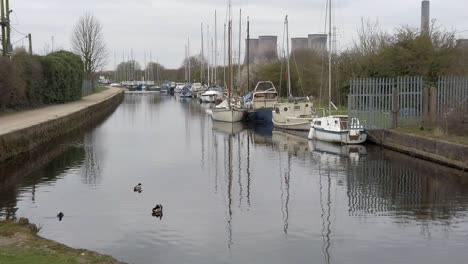 Small-sailboats-moored-on-narrow-rural-countryside-marina-canal