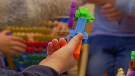 Close-shot-of-the-hands-of-a-child-playing-with-a-plastic-toy-in-preschool