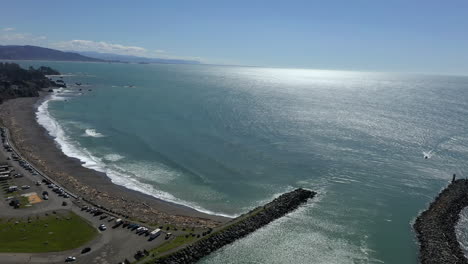 Aerial-circling-pan-shot-of-Brookings-jetty-and-beach-on-sunny-day