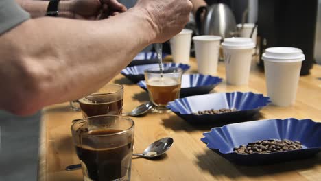 Rinsing-spoons-during-coffee-cupping-or-cup-tasting,-slow-motion-close-up