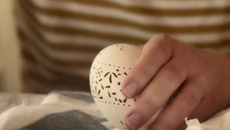Hand-carefully-decorates-ornate-pattern-on-Easter-madeira-egg,-close-up