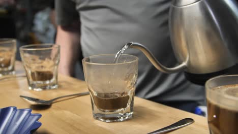 Pouring-hot-water-for-coffee-cupping-taste-test,-slow-motion-close-up