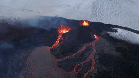 Aerial-view-away-from-volcano-craters-and-lava,-through-steam-and-blizzard---reverse,-drone-shot