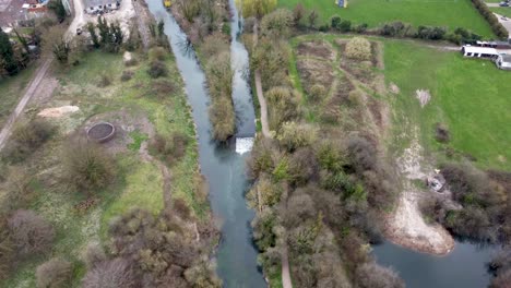 A-drone-shot-flying-over-the-rural-town-of-Chartham,-England-following-the-Stour-River