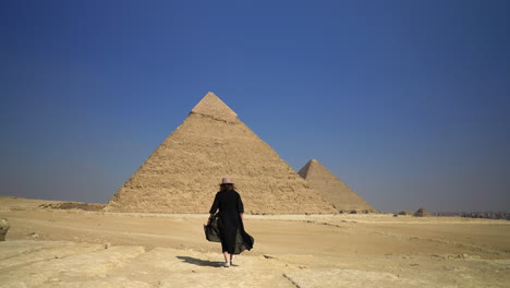 Girl-Walking-Towards-The-Pyramids-Of-Giza-In-Cairo,-Egypt---wide-shot