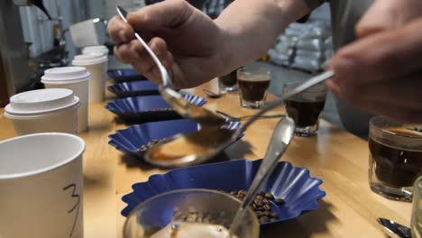 Spoons-being-rinsed-during-the-coffee-cupping-test-process,-slow-motion-close-up