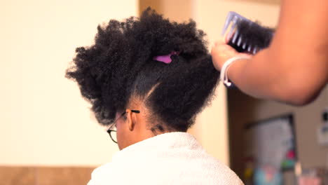 African-American-mother-styling-her-beautiful-teenage-daughter's-hair-in-a-home-salon-or-kitchen