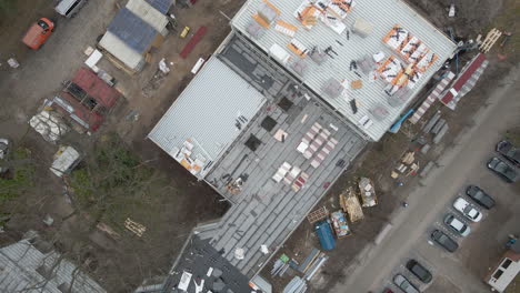 Top-down-Aerial-of-construction-worker-working-under-large-construction-site---drone-lifting-up-and-spinning