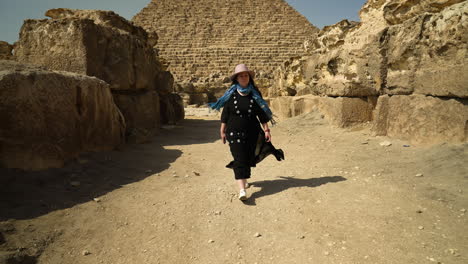 Mujer-Caminando-Frente-A-La-Pequeña-Pirámide-En-El-Cairo,-Egipto---Tiro-Inclinado-Hacia-Abajo
