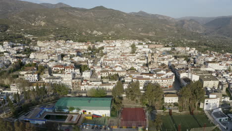 Aerial-shot-of-a-Spanish-town-with-whitewashed-buildings-surrounded-by-mountains