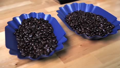 Shiny-coffee-beans-in-two-blue-bowls,-slow-motion-circle-shot