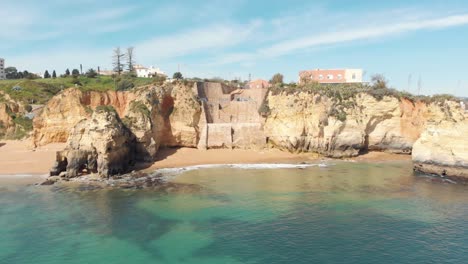 Pinhão-Beach-quiet-cove-with-picturesque-clear-waters-encircled-by-cliffs-in-Lagos,-Algarve-Portugal---Aerial-wide-Establishing-tracking-shot