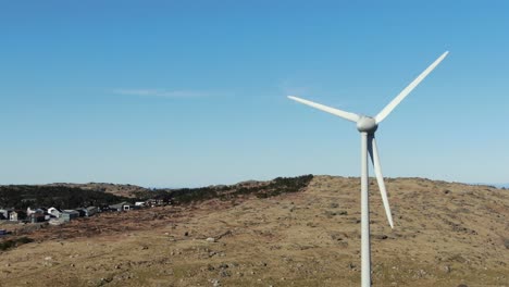 Aerial-view-of-windturbine-with-spinning-blades-in-landscape-on-a-sunny-day,-new-alternative-energy-concept,-drone-shot