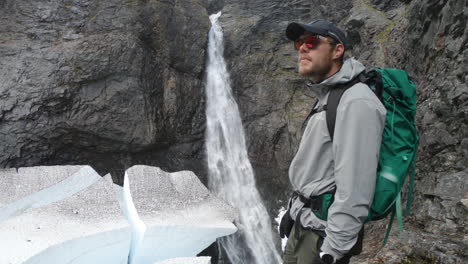 Male-hiker-with-sunglasses-looking-at-the-famous-waterfall,-Silverfallet,-Northern-Sweden