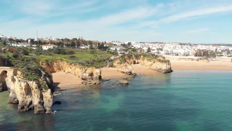 View-From-Estudante-Beach-to-Farol-de-Lagos-Molhe-Este-and-Lagos-Old-Townscape,-in-Algarve-Portugal---Aerial-Panoramic-View