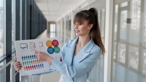 close-up-of-a-woman-in-a-business-suit-showing-on-a-slide-with-infographics-looking-at-the-camera