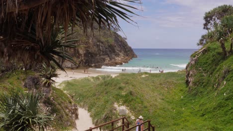 Tourist-Woman-Walking-On-Boardwalk-With-South-Gorge-Beach-In-Distance-At-Point-Lookout,-North-Stradbroke-Island,-QLD-Australia