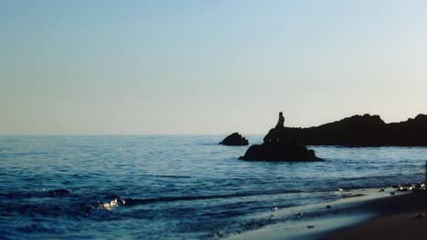 Silhouette-of-man-sitting-at-a-rock-on-the-beach