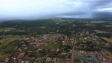 Aerial-view-of-a-town-on-the-countryside-of-Kenya,-Africa,-forest-fire-background---rising,-drone-shot