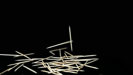 light-wooden-toothpicks-fall-in-front-of-black-background-on-dark-background-slow-motion