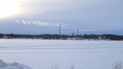 Columns-of-smoke-from-smokestacks-in-snowy-winter-landscape