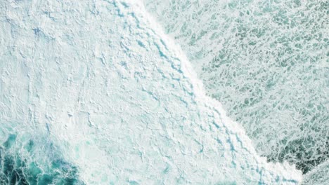 Aerial-top-down-view-of-extensive-turquoise-sea-foam,-big-waves-breaking