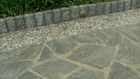 Pan-across-a-flagstone-pathway-with-a-border-of-pebbles-and-cobblestones
