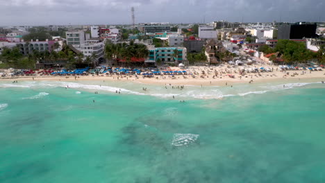 Revealing-drone-shot-of-people-on-the-beach-and-the-beach-resorts-at-Playa-Del-Carmen-Mexico
