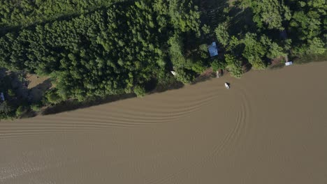 Imágenes-De-Drones-De-Un-Bote-Pequeño-En-El-Río-Amazonas-De-Aguas-Marrones-Llegando-A-Casa-Y-Haciendo-Olas-Suaves
