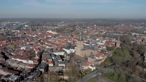 Picturesque-aerial-approach-of-medieval-Hanseatic-city-Zutphen-in-The-Netherlands-with-central-Walburgiskerk-tower-in-the-foreground-against-a-blue-sky