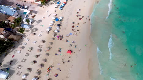 Revealing-drone-shot-of-Playa-Del-Carmen-coastline-and-resorts-with-people-on-the-beach