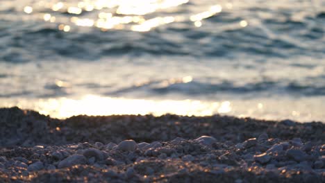 Waves-breaking-over-stone-beach-at-sunset,-tranquil-coastal-shoreline-landscape
