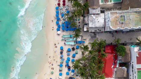 Rising-drone-shot-of-Playa-Del-Carmen-coastline-and-resorts-with-people-on-the-beach