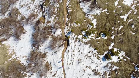 Hikers-hiking-on-a-small-mountain-path-covered-in-snow-in-winter-drone-shot