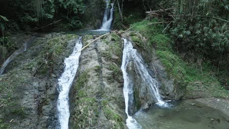 Erstaunliche-Überführung-In-Zeitlupe-Einer-Jungen-Dame,-Die-Am-Fuß-Eines-Kaskadierenden-Wasserfalls-Steht
