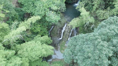 Aufsteigende-Drohnenansicht-Eines-Kaskadierenden-Wasserfalls-Tief-Im-Dschungel-In-Zeitlupe