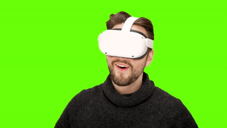 Happy-excited-man-puts-on-white-virtual-reality-VR-goggles-first-time-impressive-world-experience-headset-immersive-playing-movie-watching-green-screen-chroma-key-XR-augmented-quest-2-technology-nerd