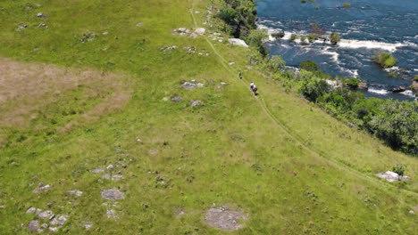 Elderly-hikers-trailing-under-the-sun-on-a-hill-by-a-beautiful-river