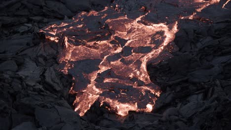 Slow-moving-viscous-lava-on-dark-basalt-rock-surface-at-night