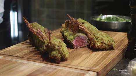 Chef-puts-venison-meat-ribs-on-wooden-cut-board-after-baking-in-oven