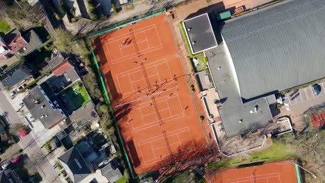 Top-down-aerial-of-busy-tennis-court---drone-lifting-up-and-spinning