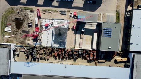 Top-down-aerial-of-large-crane-on-construction-site-on-industrial-area---drone-lifting-up