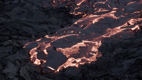 Viscous-lava-moving-slowly-on-black-rock-surface-with-solidifying-crust