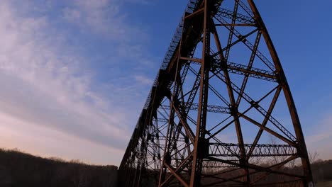 Walking-under-a-beautiful,-high,-steel,-beautifully-engineered-train-bridge-viaduct-in-the-Appalachian-Mountains-during-early-spring