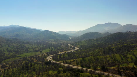 A-highway-winds-through-the-picturesque-Tehachapi-Mountains---aerial-time-lapse-on-hazy-day-in-spring