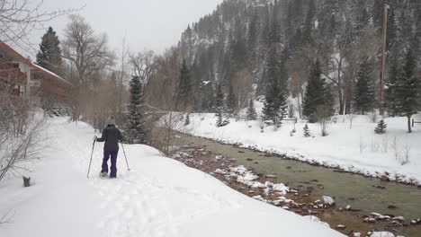 Female-in-Snowshoes-Walking-by-the-River-in-Snowy-Winter-Landscape-of-Ouray-USA,-Southwestern-Colorado