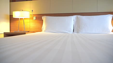 White-bed-setup-and-lamps-in-cozy-bedroom-of-luxury-hotel,-close-up-pan